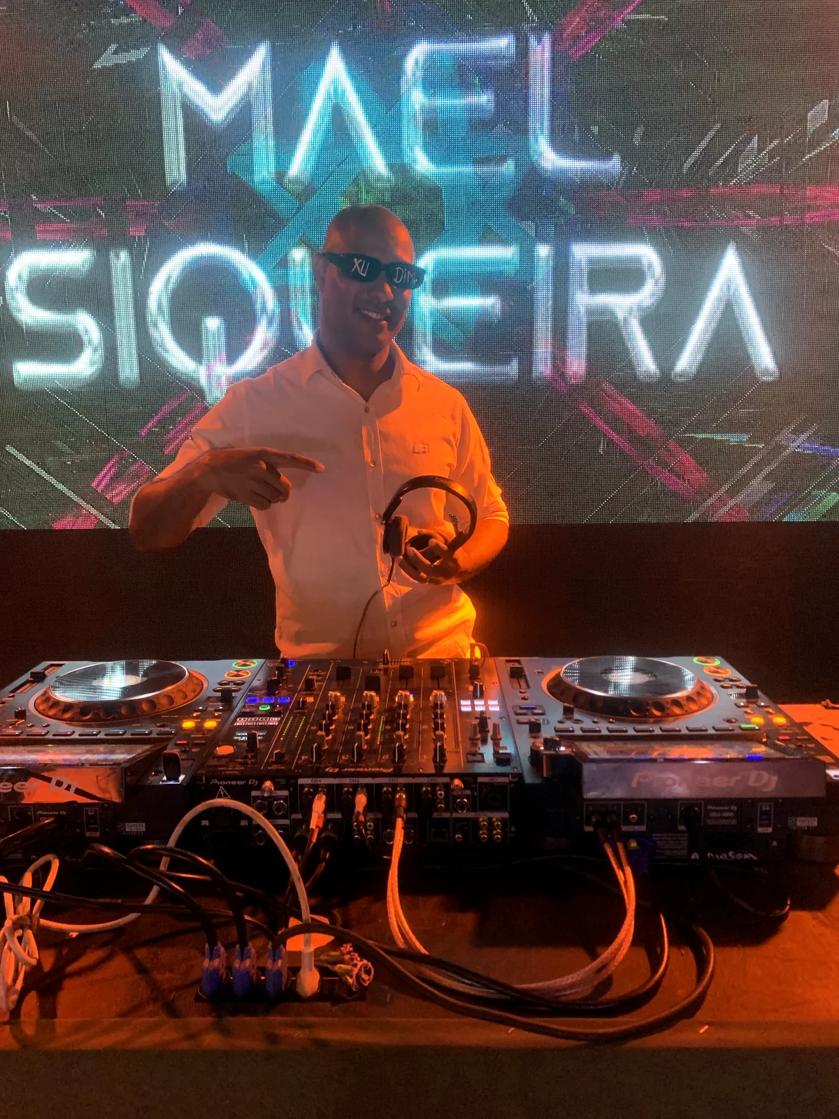 Mael Siqueira DJ diante de painel de LED com seu nome